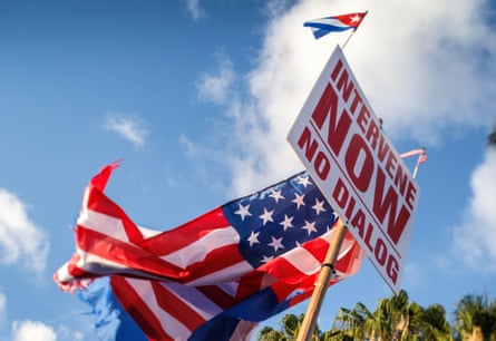 US flag and and banner that says ‘Intervene Now No Dialogue’.