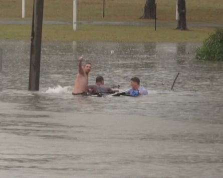 ABC reporter Will Murray, right, helps the driver of a vehicle sinking in flood water, in Morayfield, Queensland.