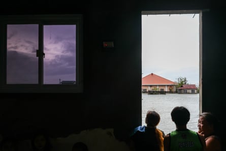 People stand in a doorway looking out on to a flooded landscape.