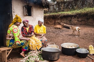 Uganda: Vanessa (far right) shares a joke with her neighbours Lillian (left) and Sharon (centre). The women are peeling potatoes to feed friends and neighbours who are helping to build a rainwater harvesting tank for Vanessa’s family. Tearfund’s partner supplied the materials, along with a craftsman, for the project in Kigezi district, south-west Uganda. Harvesting rainwater reduces long and arduous journeys to collect water.