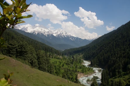 A river running between steep hillsides with snow-capped mountains in the distance.