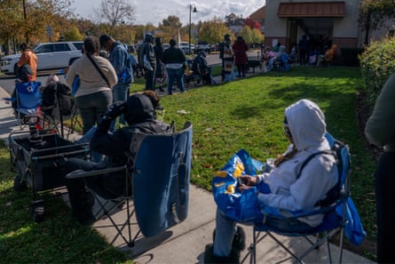 People waiting in a queue, seated on chairs.