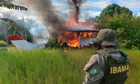 A member of the national environmental agency looking at an aircraft belonging to illegal miners being consumed by fire during an operation against Amazon deforestation, at the Yanomami territory in Roraima state, Brazil.