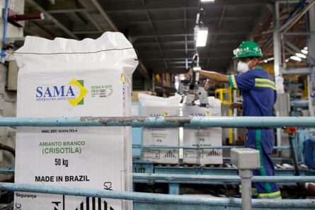 A worker in blue overalls uses a machine to fill white bags with the Sama company logo on them