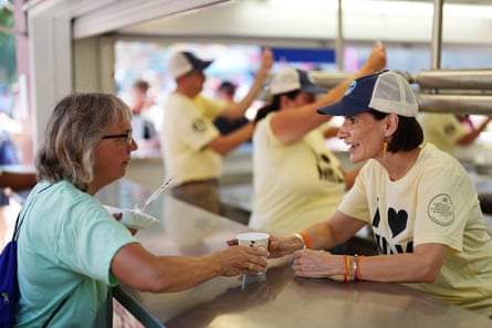 A woman hands another woman a cup of milk