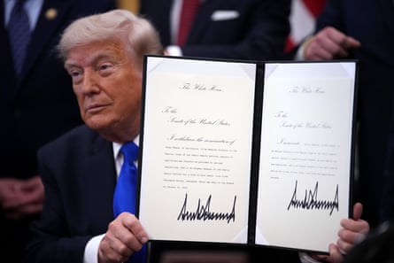 man successful suit sits astatine table and holds up signed document