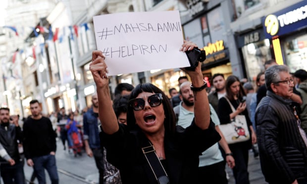 A woman holds up a piece of paper saying #mahsa.amini #helpiran at a protest in Istanbul