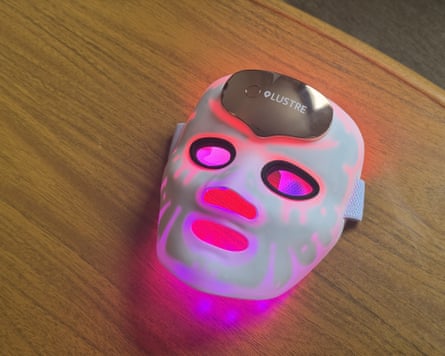 The lustre clearskin renew pro facewear led mask illuminated pink on a wooden surface