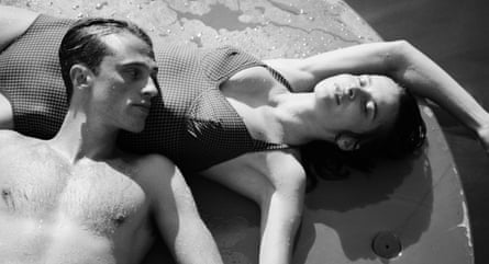 A man and a woman wearing swimwear, lying down together on a wet surface
