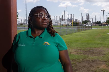a woman looks off to the side with an industrial facility in the background