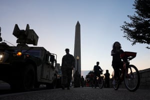 Tourists ride bicycles past US Army National Guard Humvees near the Washington Monument.