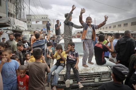 Palestinians celebrate in the street, jumping on a car