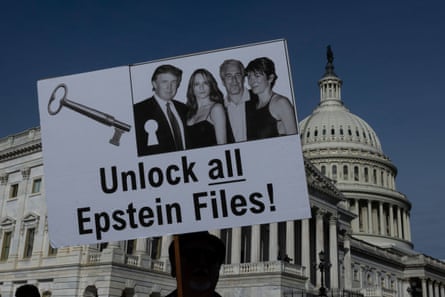 person holds up sign saying ‘unlock all epstein files!’ with a picture of a key and a group photo of four people