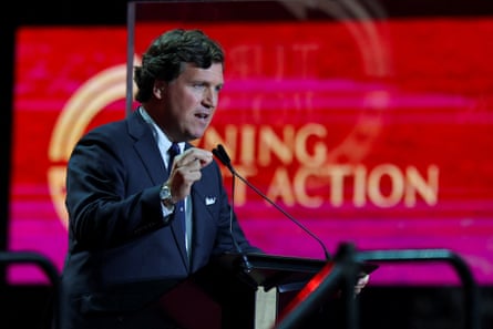 Tucker Carlson speaks into a microphone onstage