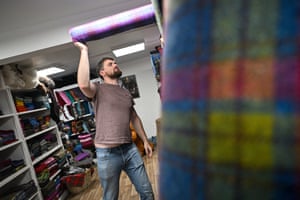 Shaun Campbell puts a roll of fabric on a high shelf