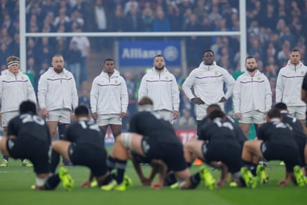 England players look on as New Zealand players perform the haka