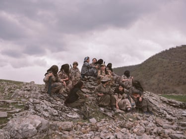 female guerrillas sit on a rocky hillside