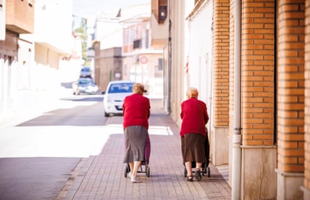 Two elderly woman walking down street seen from back