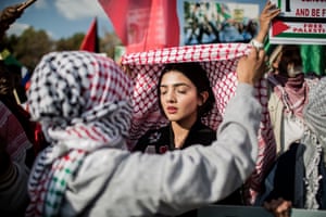 A girl ties the Palestinian keffiyeh for Attiya Dawood during a demonstration by pro-Palestinian and other civil society groups outside the US Consulate General in Johannesburg, South Africa