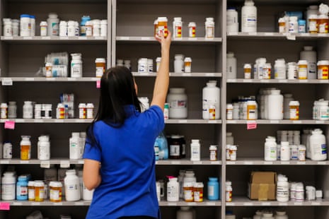 A pharmacy technician grabs a bottle of drugs