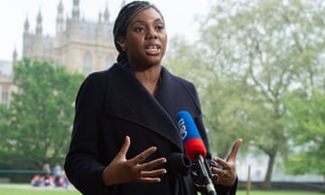 Kemi Badenoch stands behind a microphone and gestures with her hands