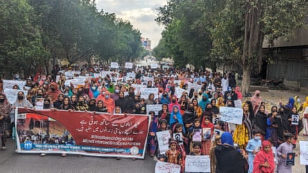 A large group of people march along the road carrying posters and placards.