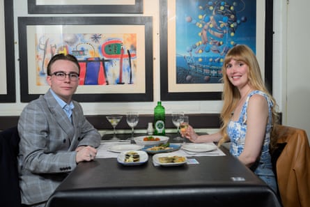 Callum and Emma sitting at a restaurant table, smiling at the camera