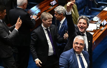 Opposition senators smile and one raises a fist into the air in the senate