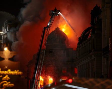 A night shot of fire fighters spraying water onto a burning dome