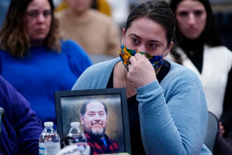 A woman tearfully holds a photograph of a smiling man.