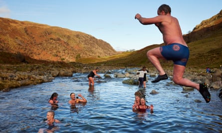A man jumps into a mountain beck pool to join other bathers