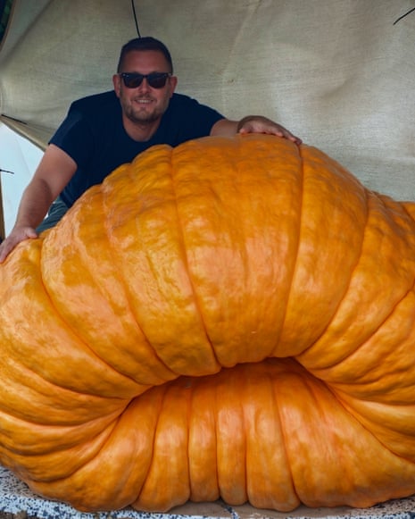 Man stands behind huge pumpkin