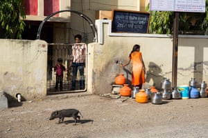 A young girl collects water from a small tap outside a hospital in the city of Latur