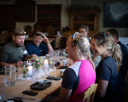 Members of the group sit talking and eating at a long wooden table