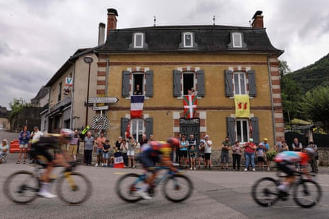 Riders pass a building sporting the French tricolore, the Basque ikurriña and the Béarn provincial flag.