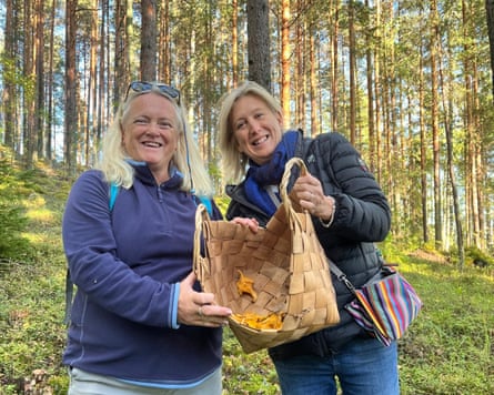 Two women in a forest holding a basket of mushrooms.