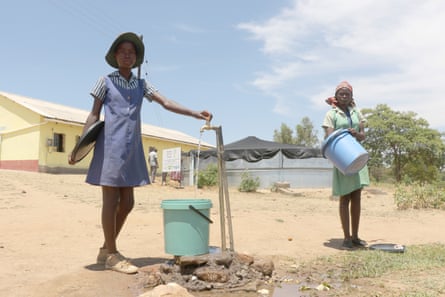 Alunos enchem um balde em uma torneira na zona rural do Zimbábue