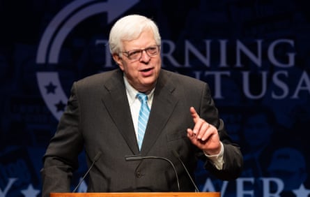 A silver-haired man wearing glasses points and speaks at a Turning Point USA event