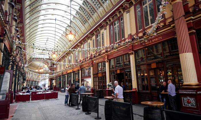 City workers drink at a bar in a largely empty Leadenhall market at lunchtime in London today. Many workers are continuing to work from home.