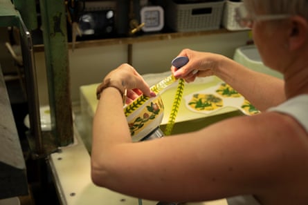 A female worker applies a strip of decoration to a ceramic item