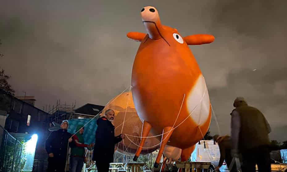 Activists parade with a giant inflatable cow to highlight the problem of methane emissions, at Glasgow climate march during Cop26 on Saturday