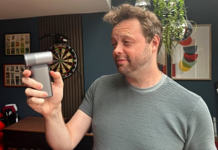 A man holds a small handheld fan to his face
