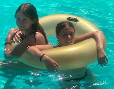 Two girls in a rubber ring inside a swimming pool