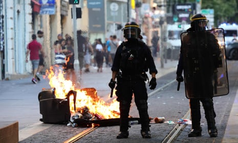 Riot police officers stand by a burning bin in Marseille.