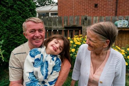 Two grandparents and a nine-year-old girl smiling as they pose for a photograph