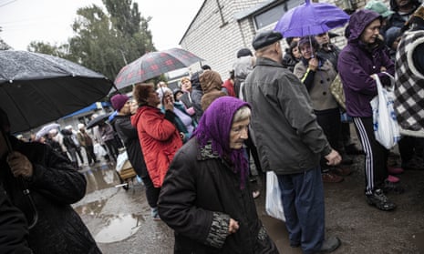 Ukrainians form long queues to receive humanitarian aid in rainy and cold weather in Kupiansk.