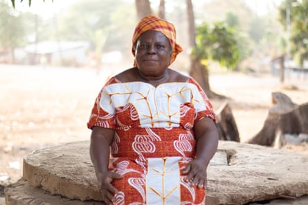 An older African woman in headdress sitting on a large capped well