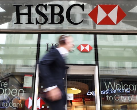 A blurry figure walks past a branch of HSBC