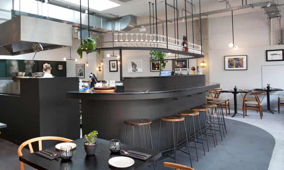 The curved gunmetal-grey bar, with stools around it and glasses on a shelf suspended from the ceiling at Cornerstone