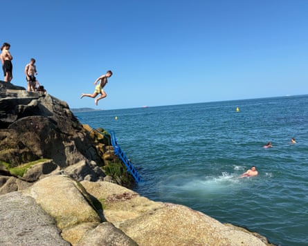 People jumping off rocks into the sea